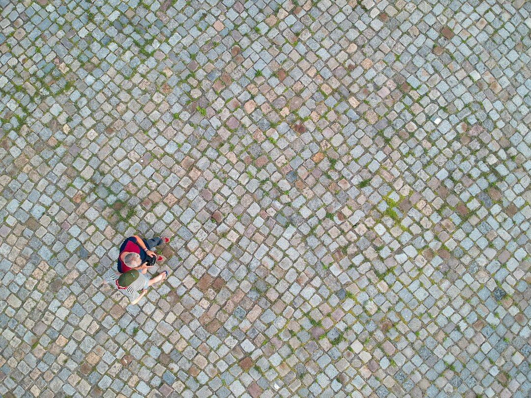 Danish documentary photographer walking through a cobblestone street with a camera